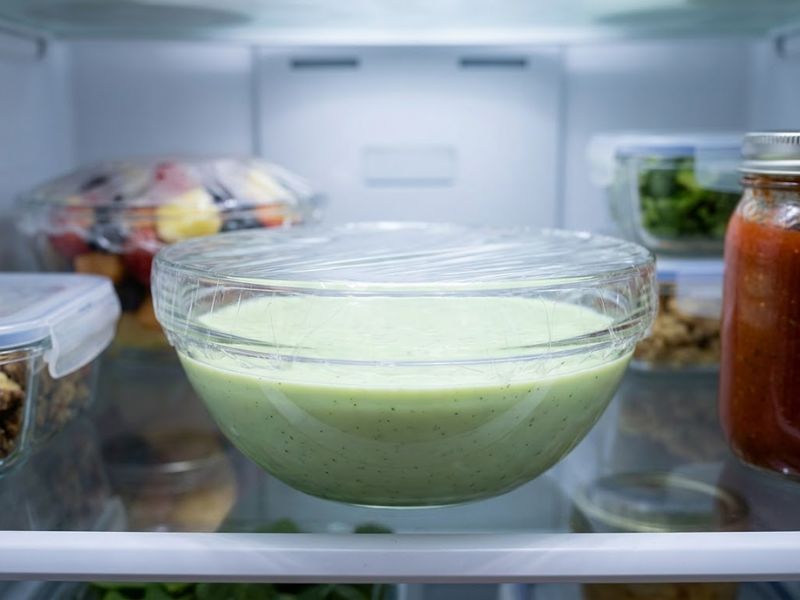 Glass bowl of mint ice cream base covered directly with plastic wrap