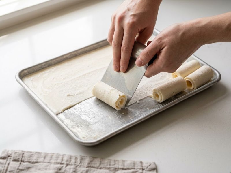 Scraping frozen ice cream into rolls