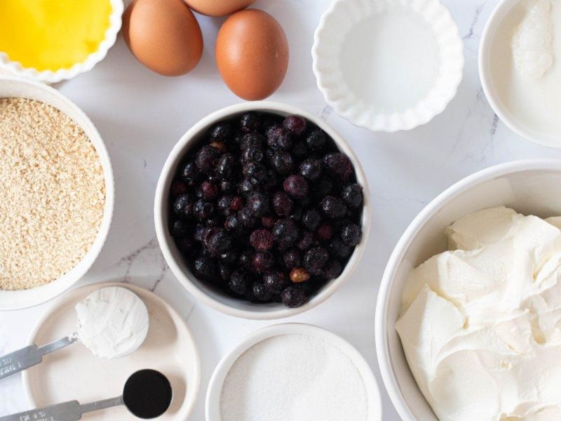 Ingredients for homemade blueberry cheesecake ice cream arranged on a counter