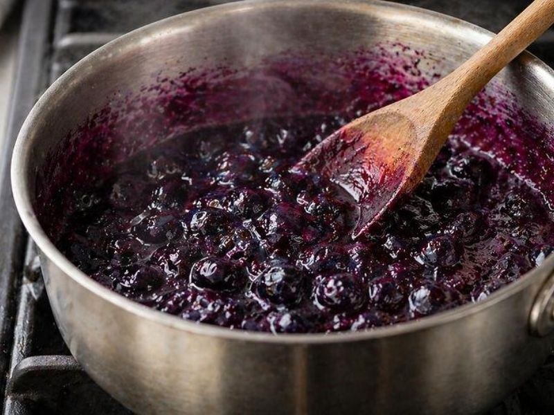 Blueberries cooking into a thick compote in a saucepan
