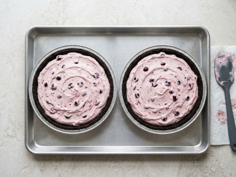 Two Oreo chocolate cookie crusts filled with creamy cherry pie mixture before freezing