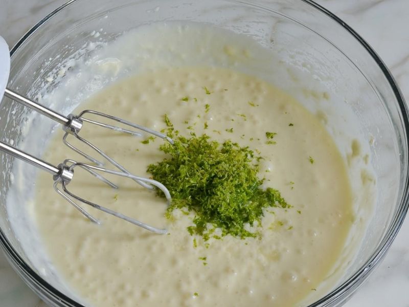 Creamy lemon ice cream mixture with fresh lemon zest being folded
